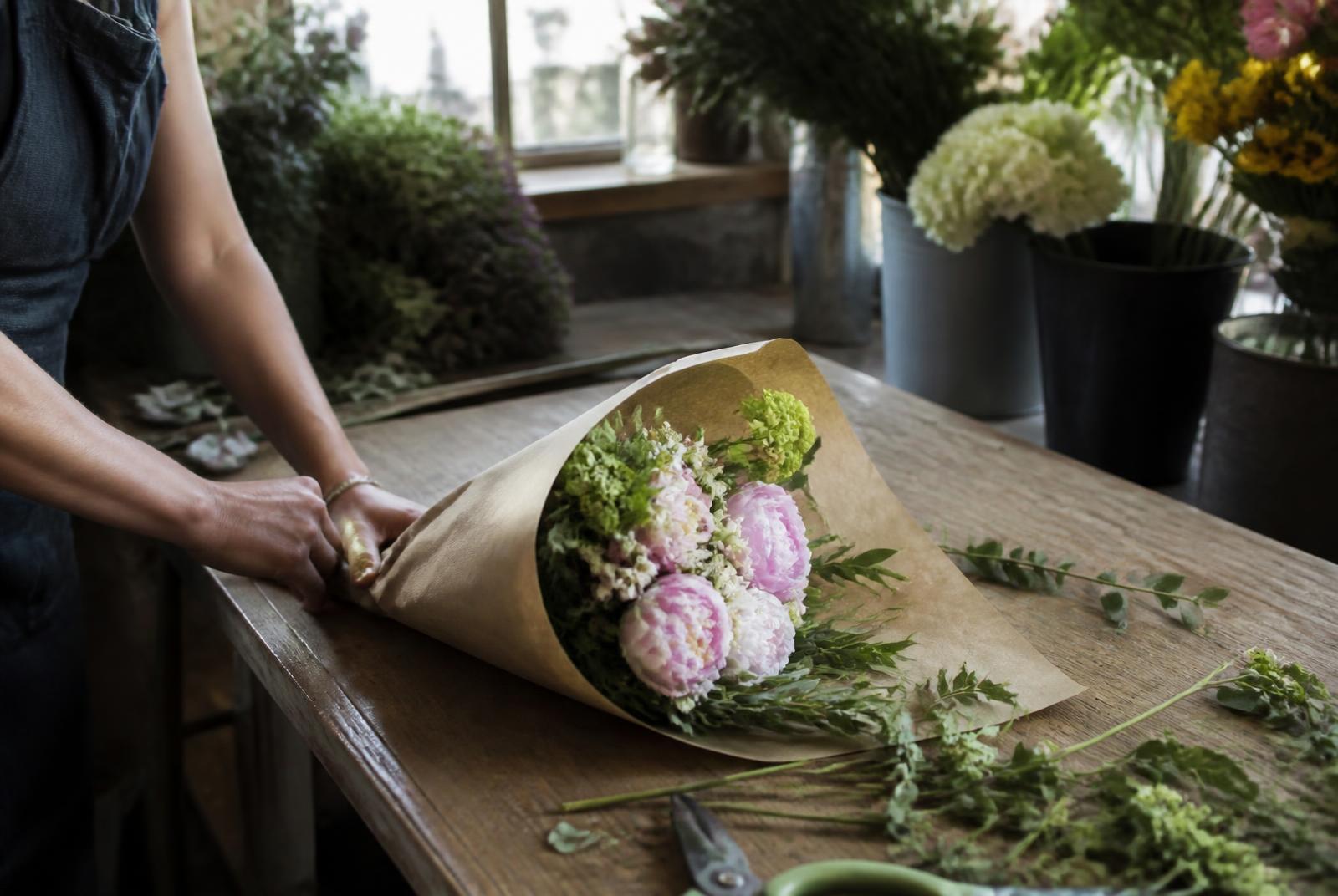 Florist wrapping a fresh bouquet in a workshop